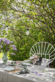 Gedeckter Tisch für Zwei unter Fliederstrauch im Garten