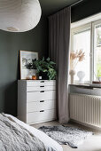 White bureau unit and sheepskin in bedroom with green walls