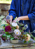 Blumengesteck arrangieren mit Dahlien (Dahlia), Kugeldistel, Heidekraut und Mohnkapseln