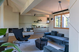 Eleganter Wohnraum mit dunkler Sofagarnitur, Couchtisch und Klassiker-Loungesessel, im Hintergrund Einbauküche