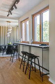 Long counter in front of the window with black bar stools, dining area in the background