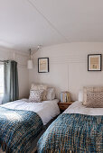 Woolen blankets on twin beds in converted Victorian railway carriage house