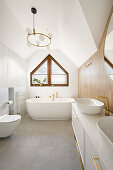 Waschtisch und freistehende Badewanne unter dem Fenster in weißem Badezimmer