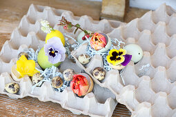 Egg carton with Easter eggs, quail eggs and pansies (Viola Wittrockiana)