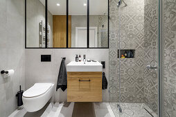 Bathroom vanity and sink and shower area in bathroom in grey tones with stoneware tiles