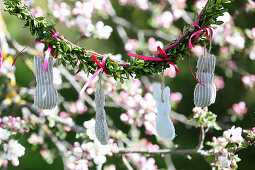 Girlande aus selbst genähten Osterhasen an blühendem Obstbaum hängend