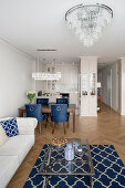 Offener Wohnraum im Hampton-Stil, helles Sofa, Esstisch mit samtblauen Stühlen