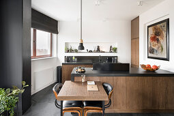Open kitchen in dark brown tones Small, folding dining table at the counter