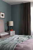 Doppelbett und Nachtisch mit Lampe im Schlafzimmer mit grauen Wänden