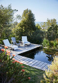 Natural pool and sun loungers on wooden deck