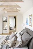 Weißes Schlafzimmer im Dachgeschoss mit Doppelbet und Kissen aus Naturstoffen