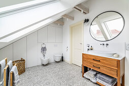 Loft-Badezimmer mit gemustertem Fliesenboden und Waschkommode mit Aufsatzbecken