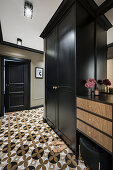 Black wardrobe with hidden washing machine and patterned tiled floor in the hallway