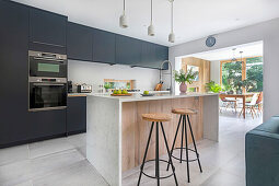 Einbauküche mit dunklen Fronten und Kücheninsel in offenem Wohnraum