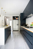 Einbauküche mit dunklen Fronten, Kühlschrank und Kücheninsel in offenem Wohnraum