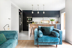 Blue upholstered furniture in open-plan living room, kitchen in the background