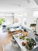 Kücheninsel mit marmorierter Arbeitsplatte und Essecke mit integrierter Sitzbank in offenem Wohnbereich