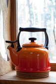Red tea kettle on windowsill