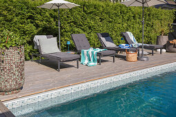 Wooden terrace with sun loungers by the swimming pool
