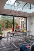 Esszimmer mit Glasdach, moderner Tischdeko und Blick in den Garten