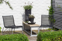 Moderne Gartenecke mit Spalier und Sitzmöbeln auf Holzdeck