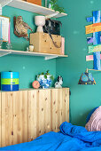 Offene Regale, darunter schmaler Holzschrank im Schlafzimmer mit blauen Wänden