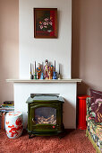 Holzofen, Kerzen und Porzellanfiguren auf Kaminsims im Wohnzimmer