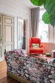 Sofa with floral pattern and vintage armchair in living room
