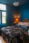 Tagesdecke mit Blumenmuster auf Doppelbett in blauem Schlafzimmer