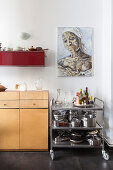 Servierwagen mit Geschirr, darüber Kunstwerk in der Küche