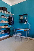Vintage Schreibplatz und offene Garderobe im Zimmer mit blauen Wänden