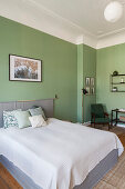 Doppelbett und Sitzecke im Schlafzimmer mit grünen Wänden