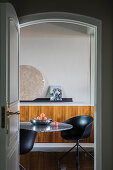 Blick durch offene Tür auf Marmortisch mit dunklen Schalenstühlen