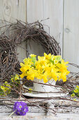 Bouquet of mini daffodils (Narcissus) and primroses in a cup, wreath of willow twigs and purple primula (Primula denticulata)
