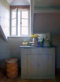 Grey chest of drawers with decorative objects in attic bedroom with small window