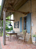 Covered, rustic veranda with table and seating furniture