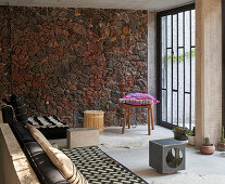Sitzbereich mit Wand aus Vulkangestein, raumhohes Fenster mit Metallgitter