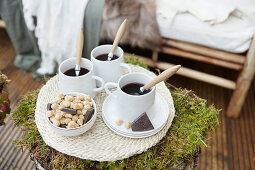 Herbstliche Teezeit auf Baumstamm mit Moos auf der Terrasse