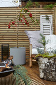 Terrasse mit Sichtschutz aus Holz, mit Bambusstuhl, Feuerschale, Topfpflanze und Dekoration