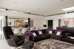 Braunes Ecksofa mit Kissen und farblich passender Sessel in offenem Wohnraum