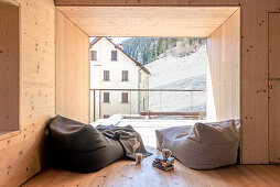 Holzverkleidetes Zimmer mit Sitzsäcken und Blick auf Bergwiese