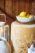 Lemons in ceramic bowl on beige pouf next to metal lantern