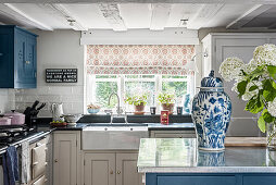 Country-style kitchen with blue cabinet fronts and fresh cut hydrangea