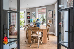Dining room with wooden table and rattan chairs, decorated with art and patterned blinds