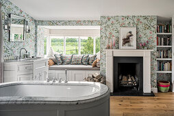 Bathroom with floral wallpaper and cozy seating area by the window