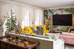 Farbenfrohes Wohnzimmer mit handgemalter Wandtapete und gelbem Sofa