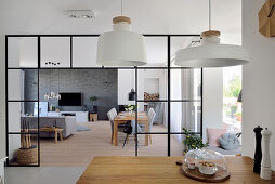 Offener Wohnbereich mit modernen Pendelleuchten und Glasraumteiler