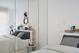 Weißes Schlafzimmer mit Regal und Spiegel in kleiner Wohnung
