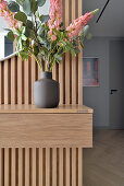 Holzkonsole mit Vase und Blumen im modernen Apartment