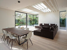Open-plan living and dining area with wooden table, modern sofa and garden view